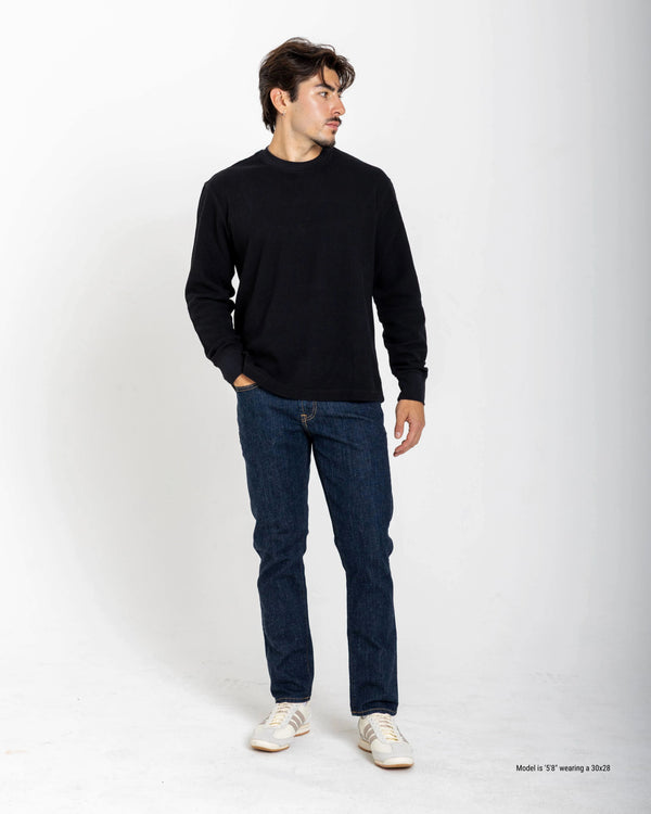 Shorter Man wearing a black long-sleeve shirt and blue jeans on a white background