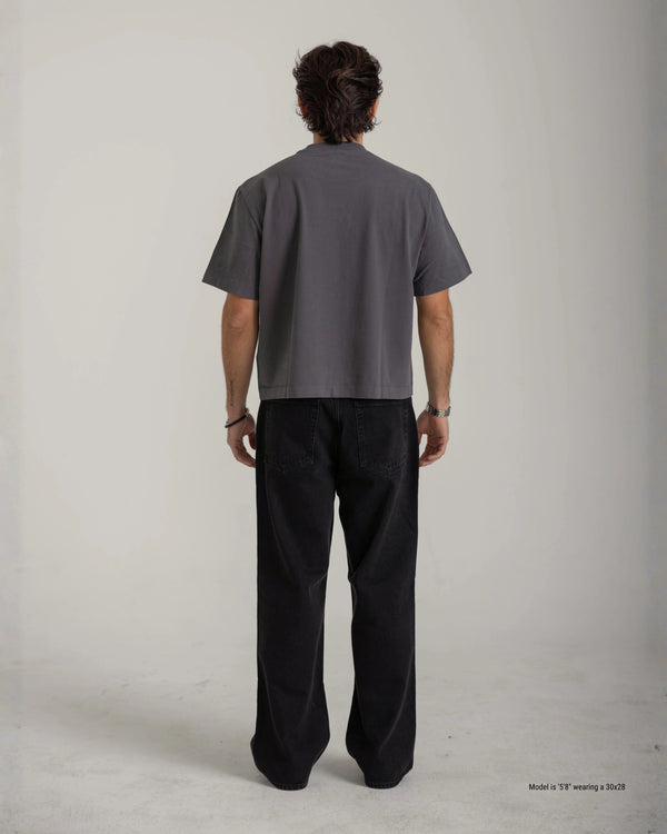 Person wearing a gray t-shirt and black pants on a plain background