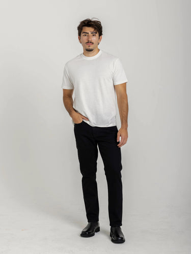 Man wearing a white t-shirt, black pants, and black shoes on a plain background