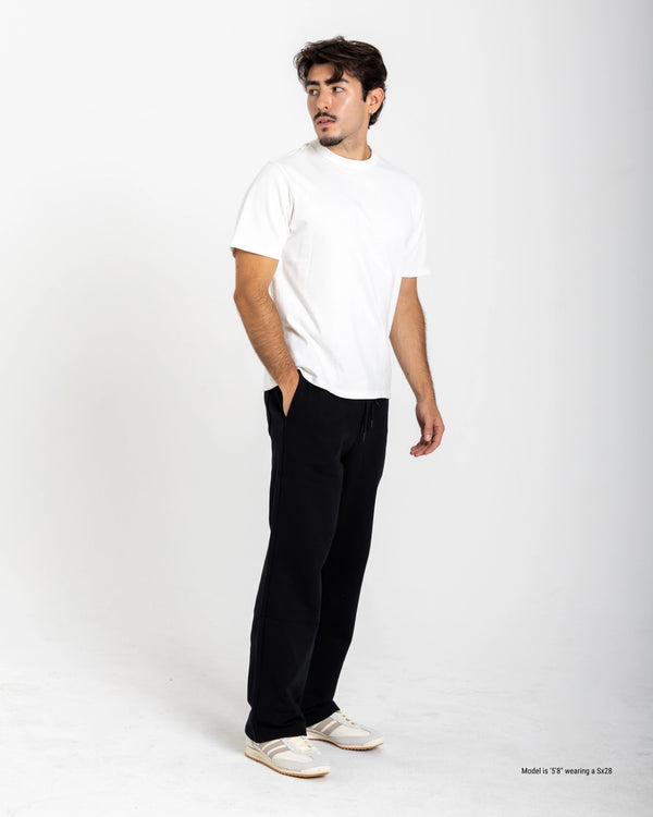 Man wearing a white t-shirt and black pants on a white background