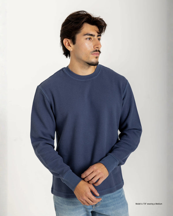 Man wearing a blue textured sweater against a white background