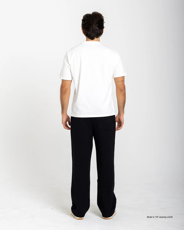 Short man wearing a white shirt and black pants on a white background