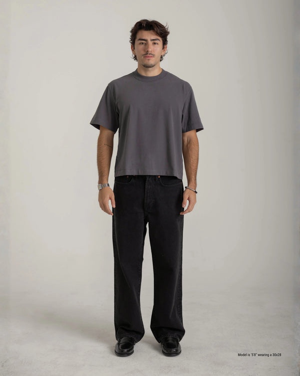 Man wearing a gray t-shirt and black pants on a plain background