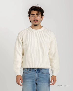 Shorter Man wearing a navy blue sweater and jeans against a white background