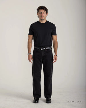 Man wearing a black t-shirt and black pants on a plain background