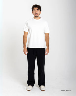 Man wearing a white t-shirt and black pants on a white background