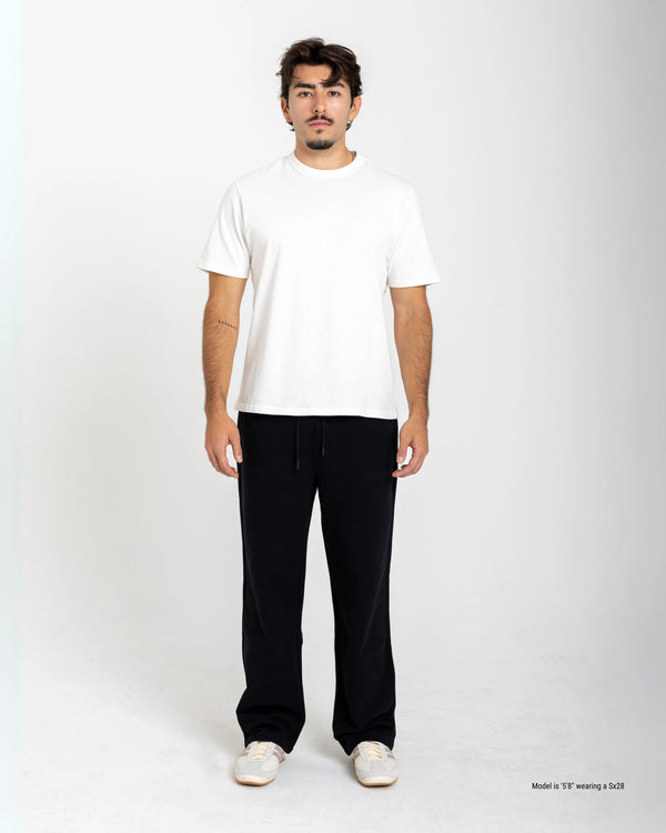 Man wearing a white t-shirt and black pants on a white background