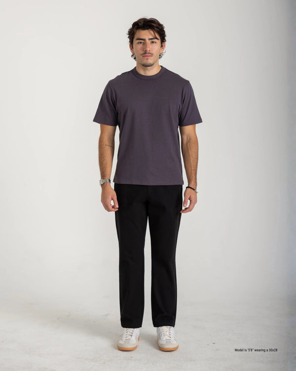 Man wearing a dark gray t-shirt and black pants on a white background