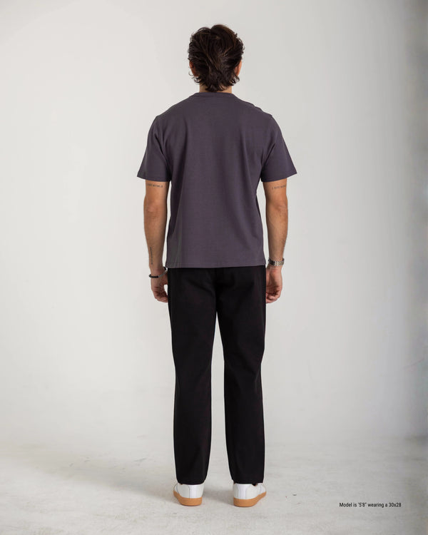 Person wearing a dark gray t-shirt and black pants on a white background