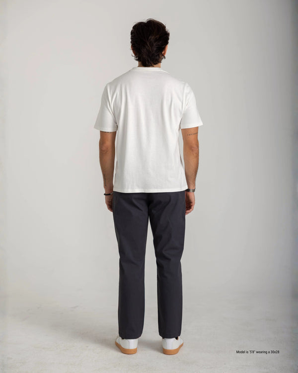 Person wearing a white t-shirt and dark pants on a plain background