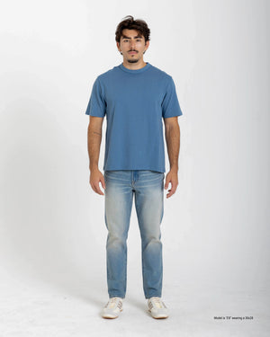 Shorter Man wearing a blue t-shirt and light blue jeans on a white background
